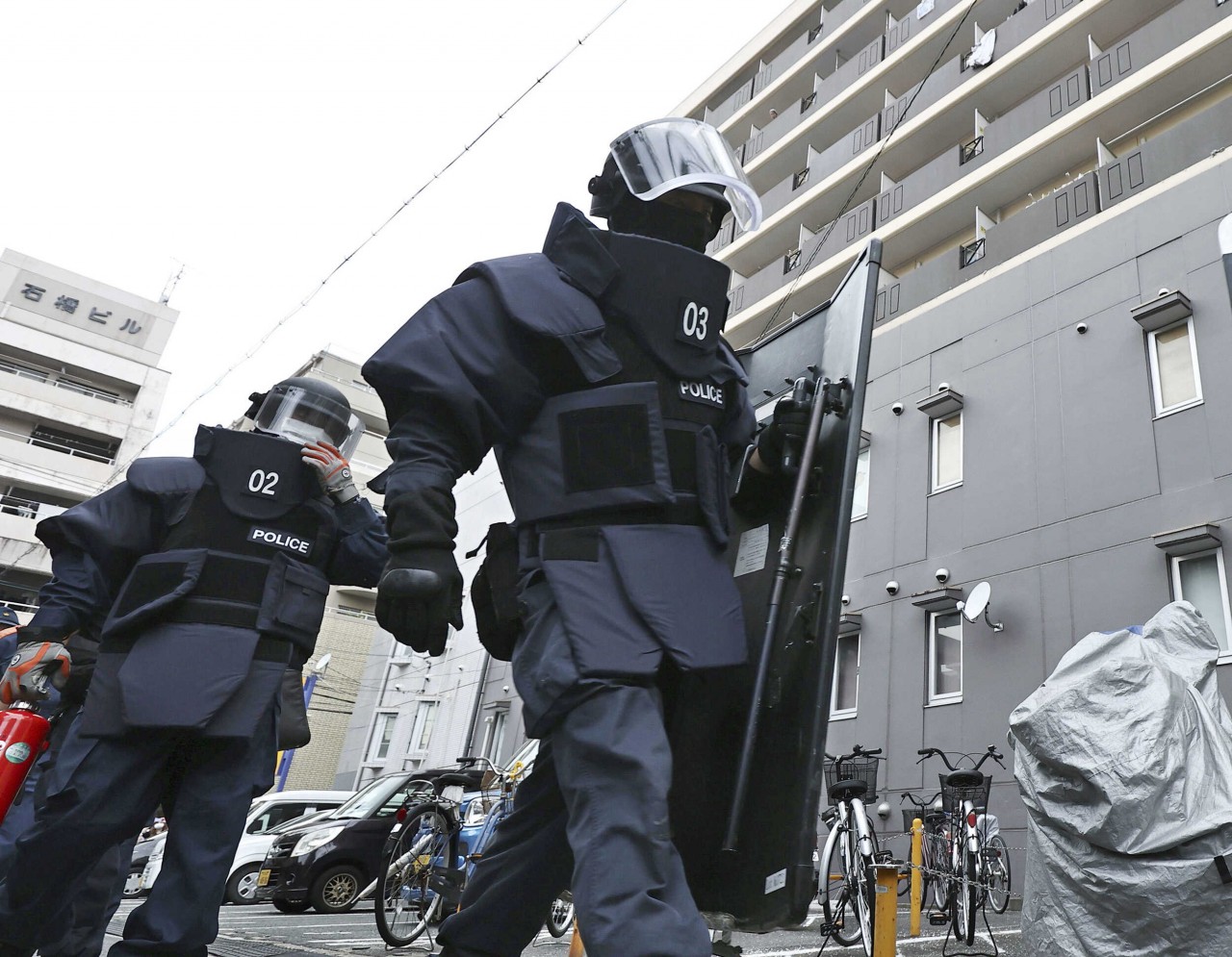 Police investigators head to a condominium owned by the man in custody for the shooting of former Japanese Prime Minister Shinzo Abe in Nara, Japan, on July 8. (Kyodo/Reuters) Police investigators head to a condominium owned by the man in custody for the shooting of former Japanese Prime Minister Shinzo Abe in Nara, Japan, on July 8. (Kyodo/Reuters)