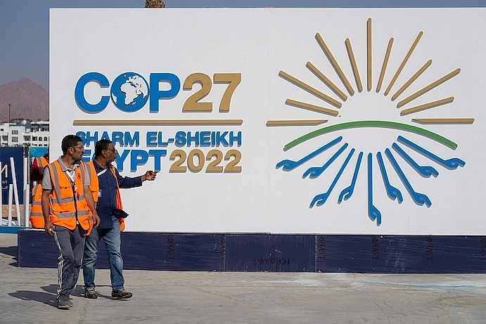 Workers pass by a sign at the convention center hosting the COP27 U.N. Climate Summit in Sharm el-Sheikh on Saturday. (Peter Dejong/AP) Workers pass by a sign at the convention center hosting the COP27 U.N. Climate Summit in Sharm el-Sheikh on Saturday. (Peter Dejong/AP)