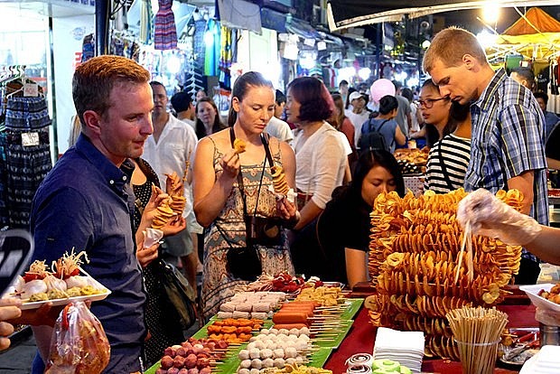 Foreign visitors enjoy street foods at Hanoi's night market. (Photo: thanhnien.vn) Foreign visitors enjoy street foods at Hanoi's night market. (Photo: thanhnien.vn)