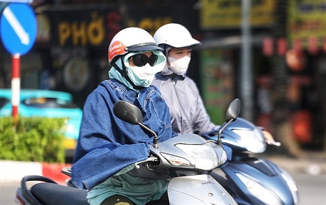 People covering up to avoid the scorching sun when going out. Photo: VNA People covering up to avoid the scorching sun when going out. Photo: VNA