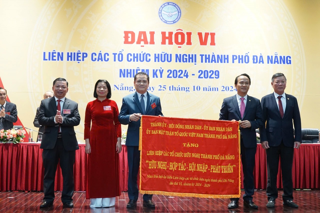 Nguyen Dinh Vinh, Permanent Deputy Secretary of the Da Nang City Party Committee (second from right), and Mr. Le Van Trung, Chairman of the Vietnam Fatherland Front Committee of Da Nang City (far right), present a banner with the message Da Nang Union of Friendship Organizations Share Future Plans