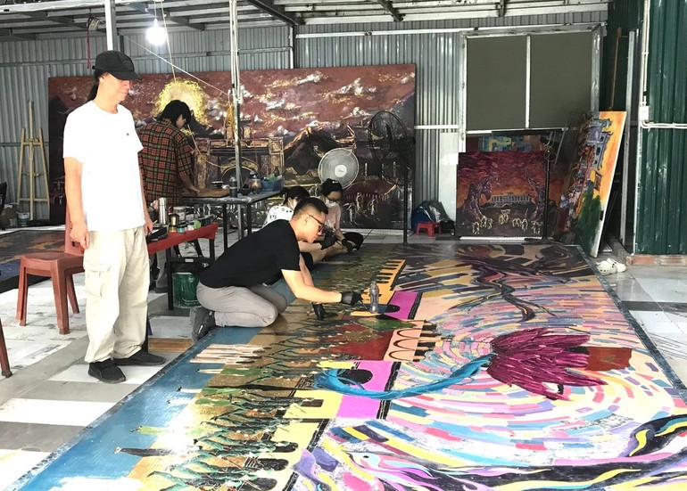Painter Chu Nhat Quang working on the completion of the painting with feedback from his father, Meritorious Artist Chu Luong. Painter Chu Nhat Quang working on the completion of the painting with feedback from his father, Meritorious Artist Chu Luong.