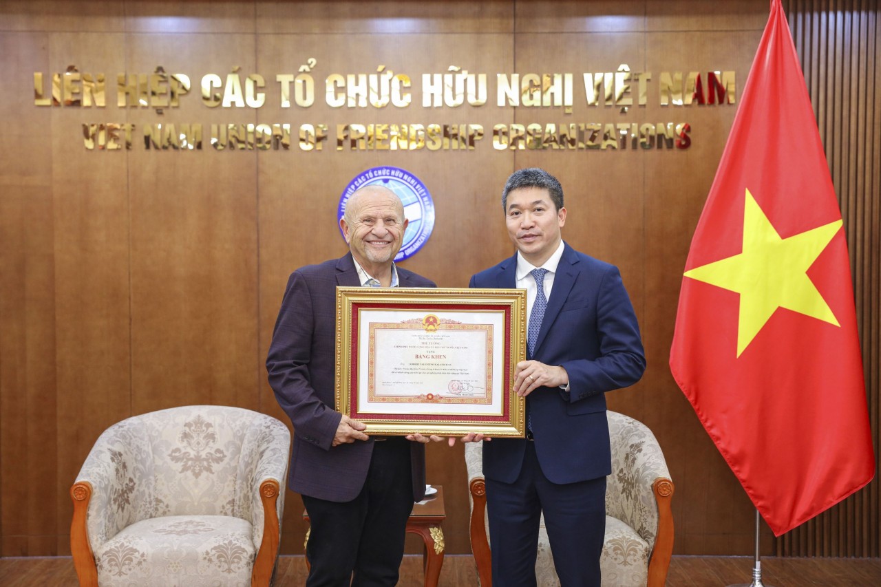 President of the Vietnam Union of Friendship Organizations (right), presents the Prime Minister’s Certificate of Merit to Mr. Robert Valentino Kalatschan, Founder and President of Giving It Back to Kids, on January 9, 2025, in Hanoi. (Photo: Dinh Hoa)