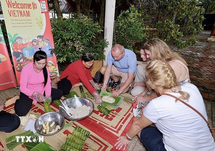 Foreign visitors experience making banh tet (cylindrical sticky rice cakes) (Photo: VNA)
