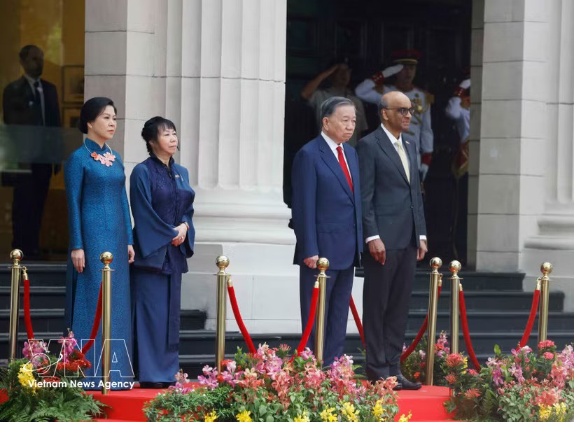 Party General Secretary and State President To Lam and Singaporean President Tharman Shanmugaratnam, together with their spouses, stand on the podium of honour as military bands perform the national anthems of Vietnam and Singapore at the welcome ceremony on May 29 morning. (Photo: VNA) Party General Secretary and State President To Lam and Singaporean President Tharman Shanmugaratnam, together with their spouses, stand on the podium of honour as military bands perform the national anthems of Vietnam and Singapore at the welcome ceremony on May 29 morning. (Photo: VNA)