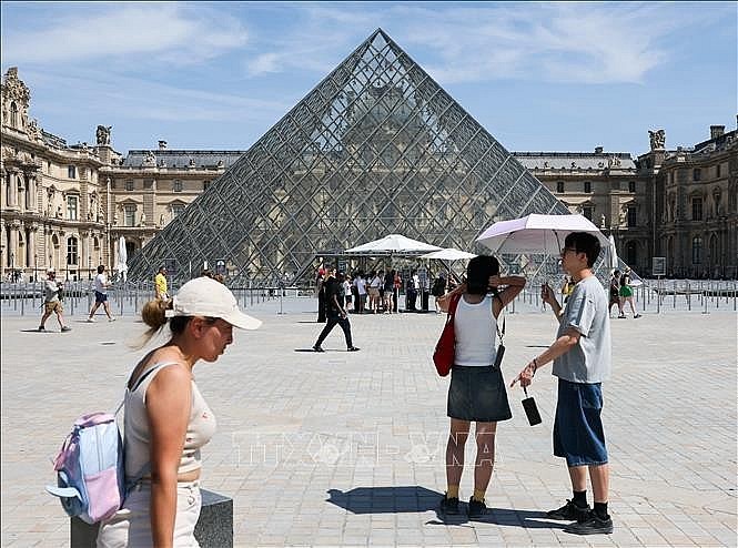 Tourists use umbrellas to shield themselves from the sun while visiting the Louvre Museum in Paris, France, on June 25, 2026. (Photo: VNA) Tourists use umbrellas to shield themselves from the sun while visiting the Louvre Museum in Paris, France, on June 25, 2026. (Photo: VNA)