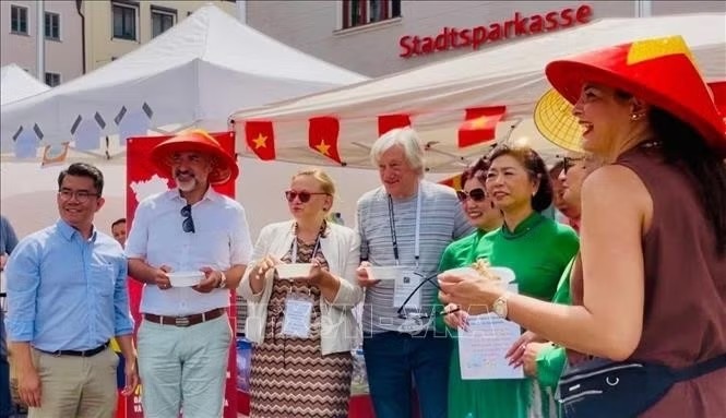 Head of the Integration and Social Affairs Department of Augsburg Martin Schenkelberg (wearing conical hat) visited Vietnamese pavilion (Photo: Nhan Dan) Head of the Integration and Social Affairs Department of Augsburg Martin Schenkelberg (wearing conical hat) visited Vietnamese pavilion (Photo: Nhan Dan)