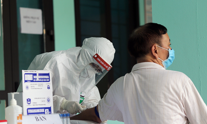 A medical staff takes samples from a man to test for the novel coronavirus in Hanoi. Photo by VnExpress 0511 covid