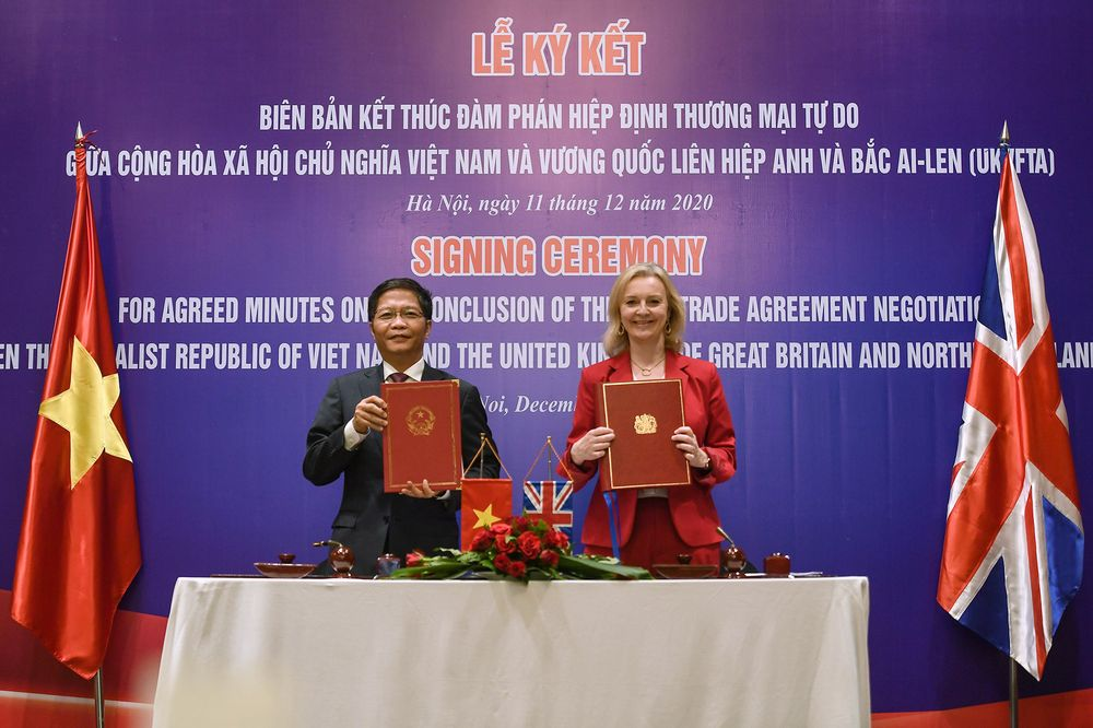 Tran Tuan Anh and Liz Truss hold up documents for a free trade agreement in Hanoi on Dec. 11. Photographer: Nhac Nguyen/AFP 1627 uk2