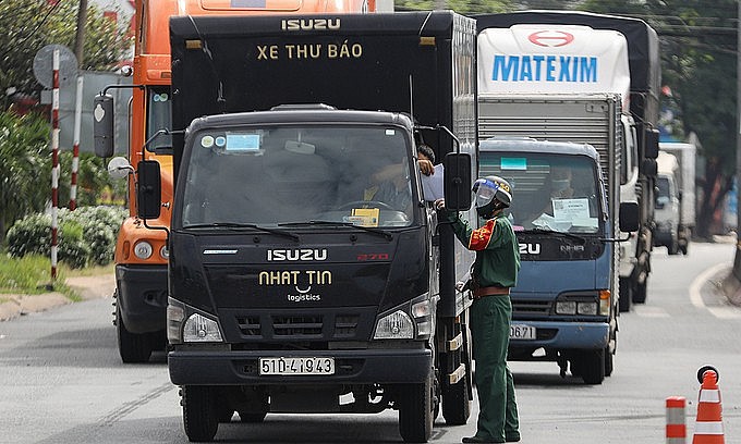 A military officer checks the travel paper of a truck at a Covid-19 checkpoint in HCMC. Photo: VnExpress