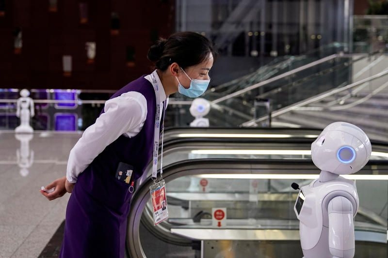A staff member, wearing a face mask following the Covid-19 outbreak, is looking at a robot at the venue for the World Artificial Intelligence Conference (WAIC) in Shanghai, China. Prompted by the need to contain Covid-19, the world is now looking toward AI-based techniques to aid the anti-pandemic fight. Photo: Reuters 1054 753358